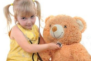 Девочка слушает стетоскопом медведя
