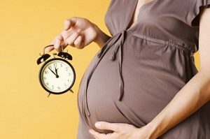 Беременная девушка держит в руках часы