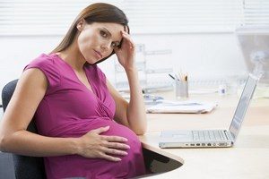 Беременная девушка сидит за ноутбуком