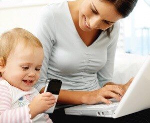 Девушка сидит за компьютером, ребенок рядом с телефоном