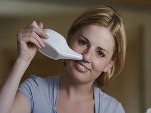 Девушка промывает нос с помощью чайничка