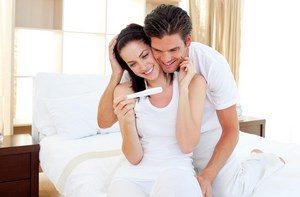Мужчина и женина смотрят на тест на беременность