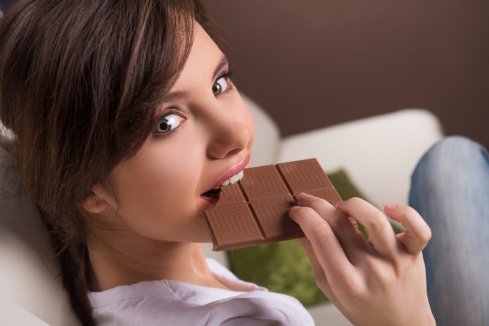 Девушка ест шоколад