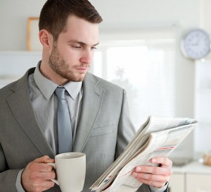 Businessman drinking coffee while reading the news